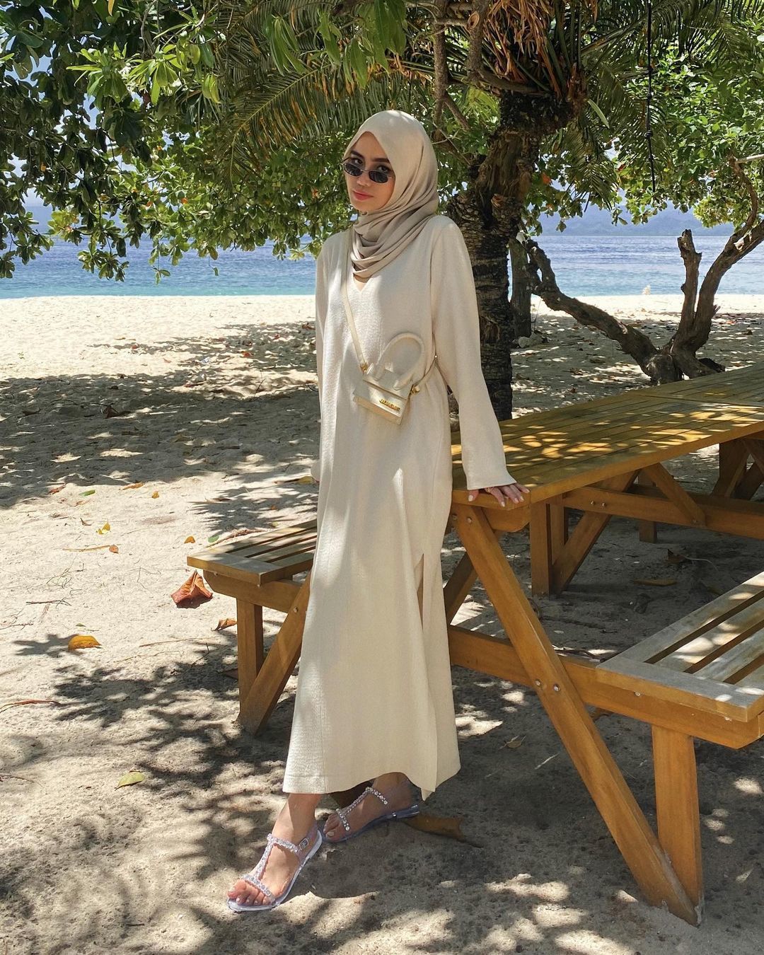 wanita hijaber memakai dress dan kacamata berdiri di pantai