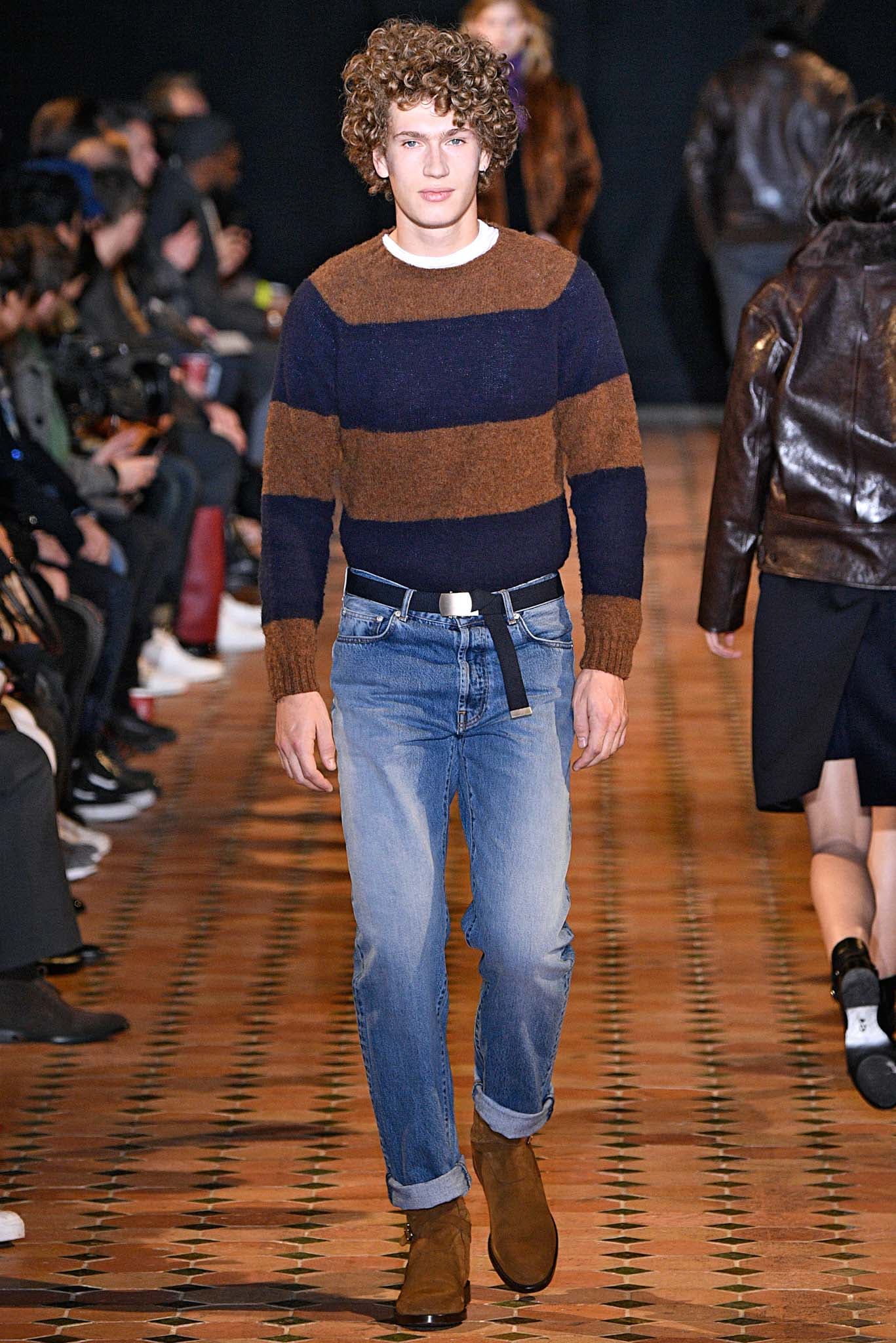 Curly hairstyles for men: Man on runway with light brown spiral curls hair wearing a stripe jumper.