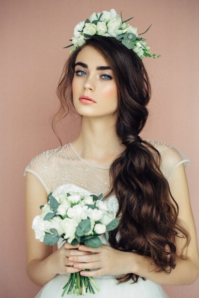 woman with very long brown wavy hair styled in a side ponytail