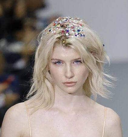 Party hairstyles: Woman with shoulder length bleach blonde hair with glitter roots on catwalk runway.