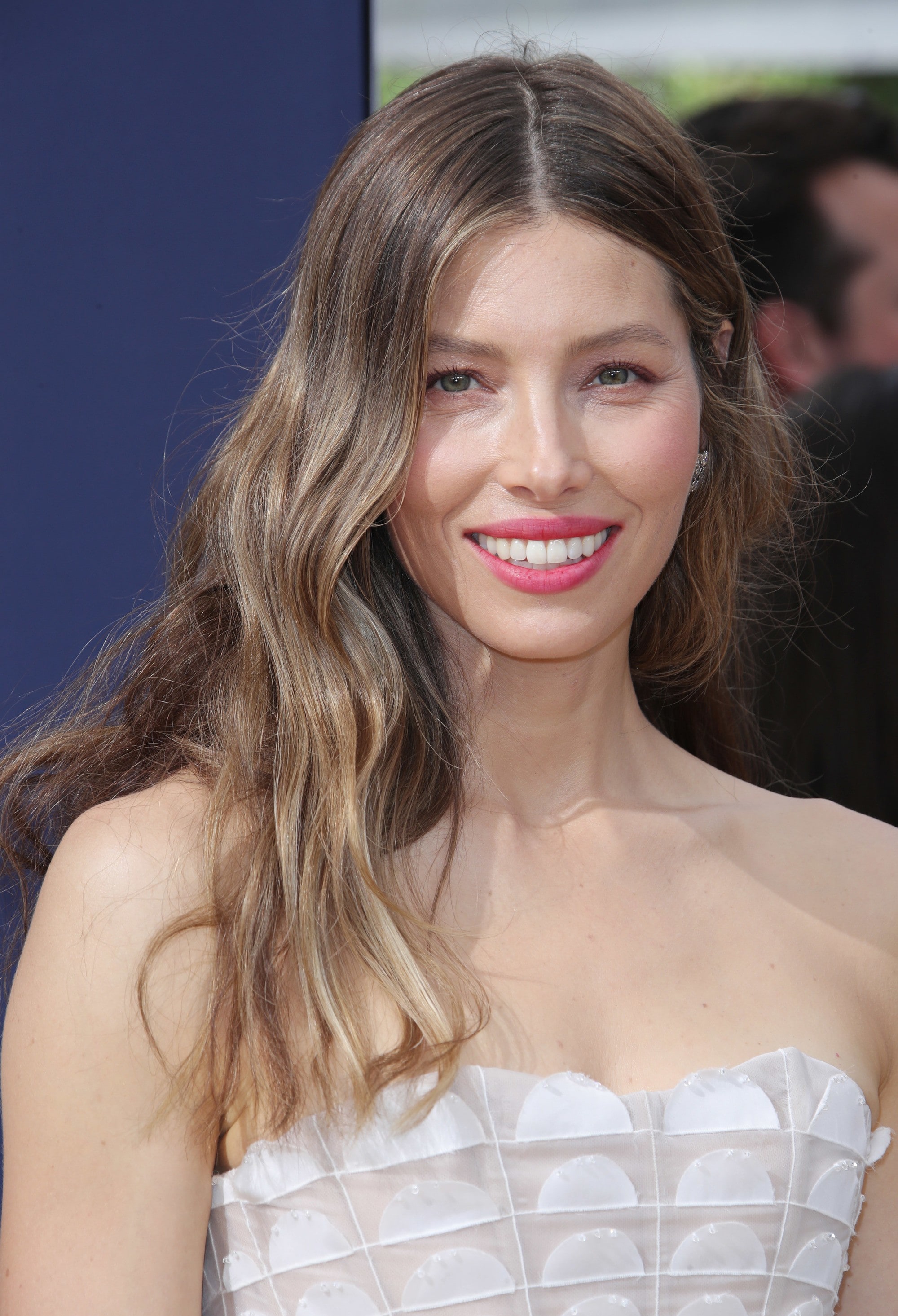 Jessica Biel com cabelo castanho cinzento com cabelo caramelo arenoso, usando a parte de cima branca no tapete vermelho