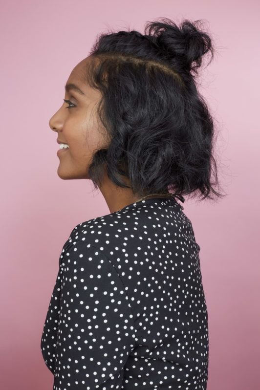 How to braid short hair: Side profile photo of All Things Hair Global Senior Producer Elise with a half-up braided bun and wavy bob
