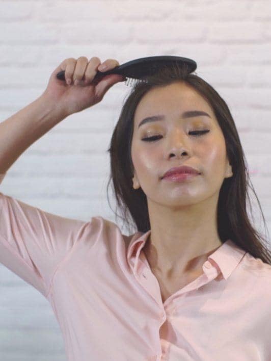 How to blow out hair: Asian woman drying her hair using a wet brush