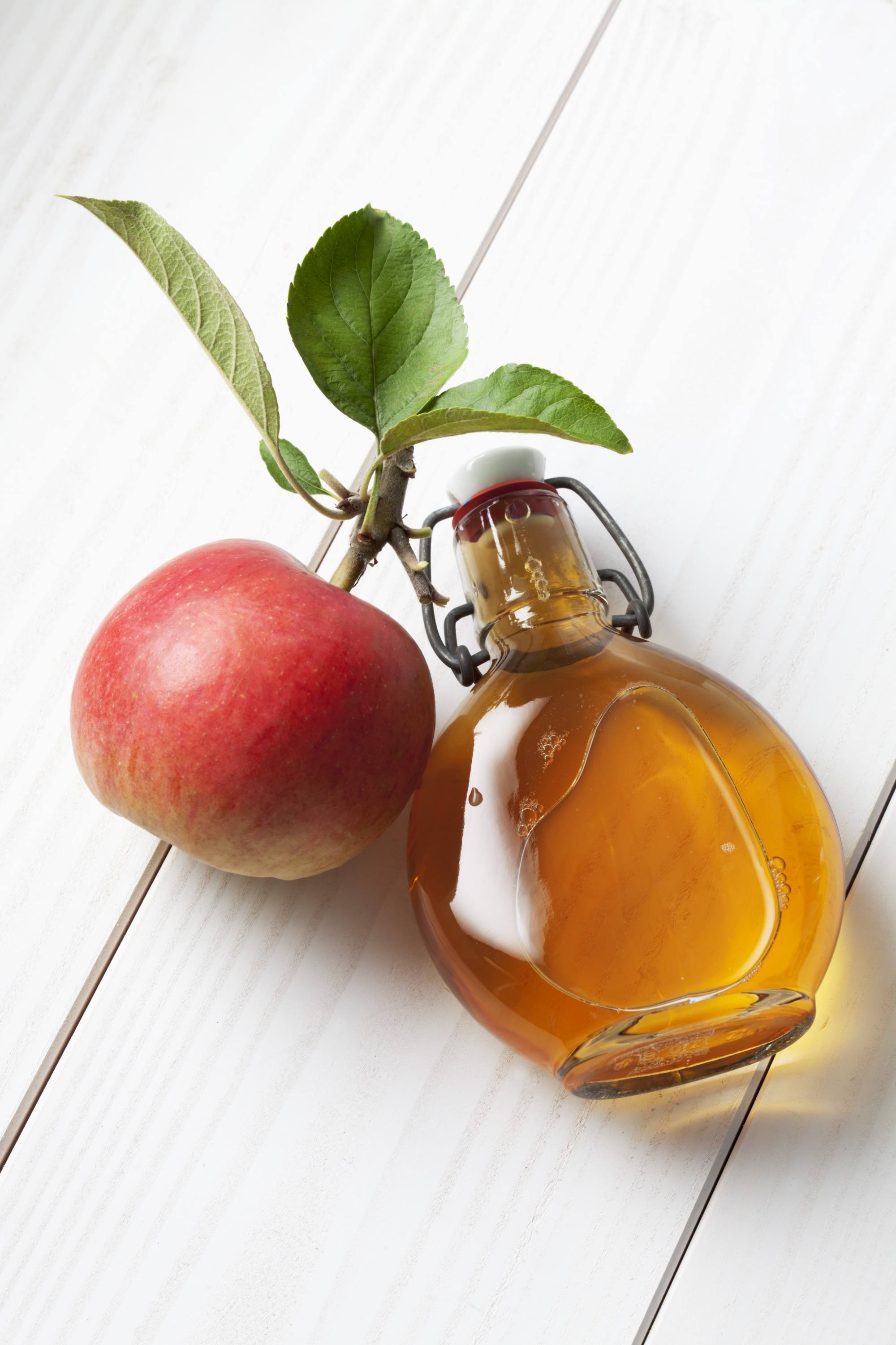 Natural dandruff remedies: an apple beside a bottle of apple cider vinegar