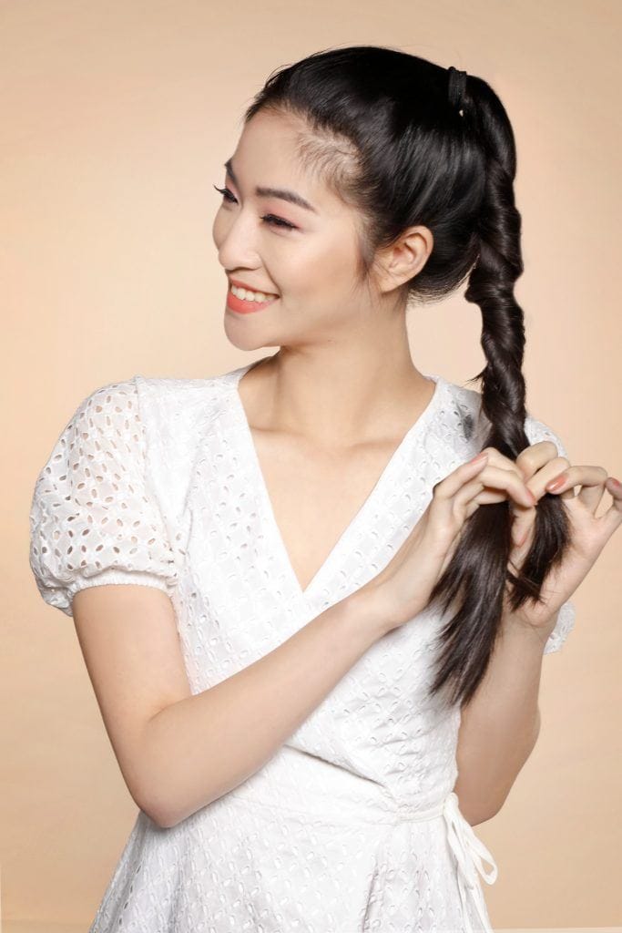 Girl is seen braiding her hair to complete one of the easy hairstyles for women