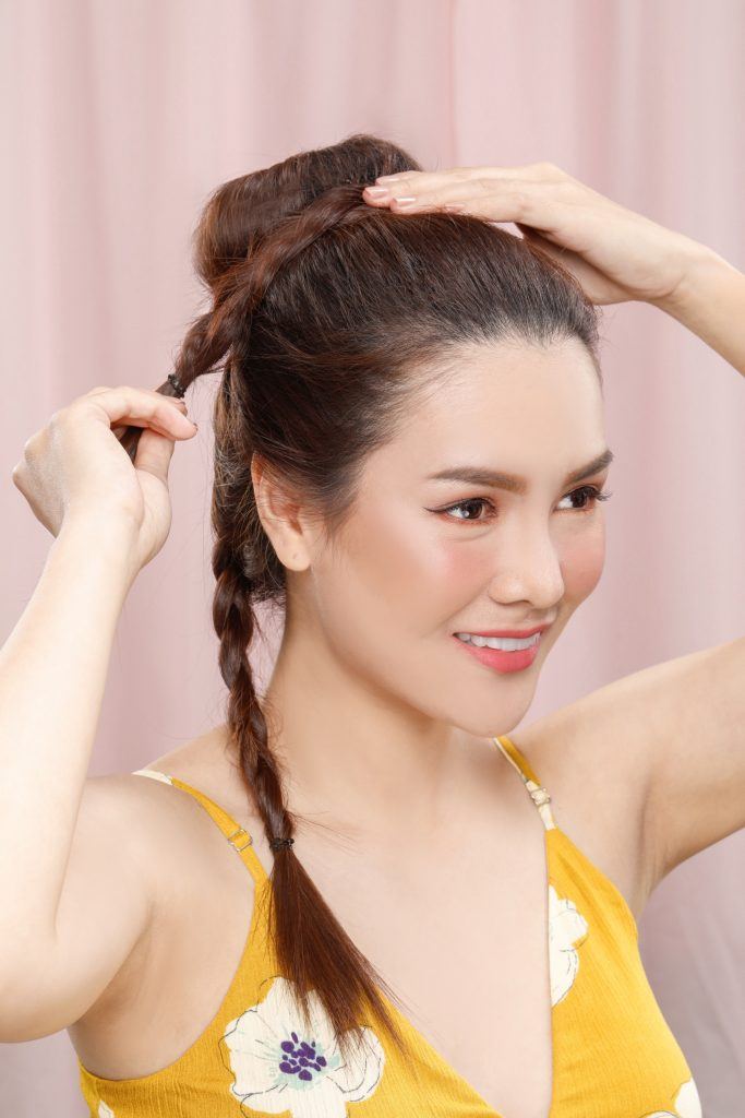 Asian woman creating a top bun with braid hairstyle